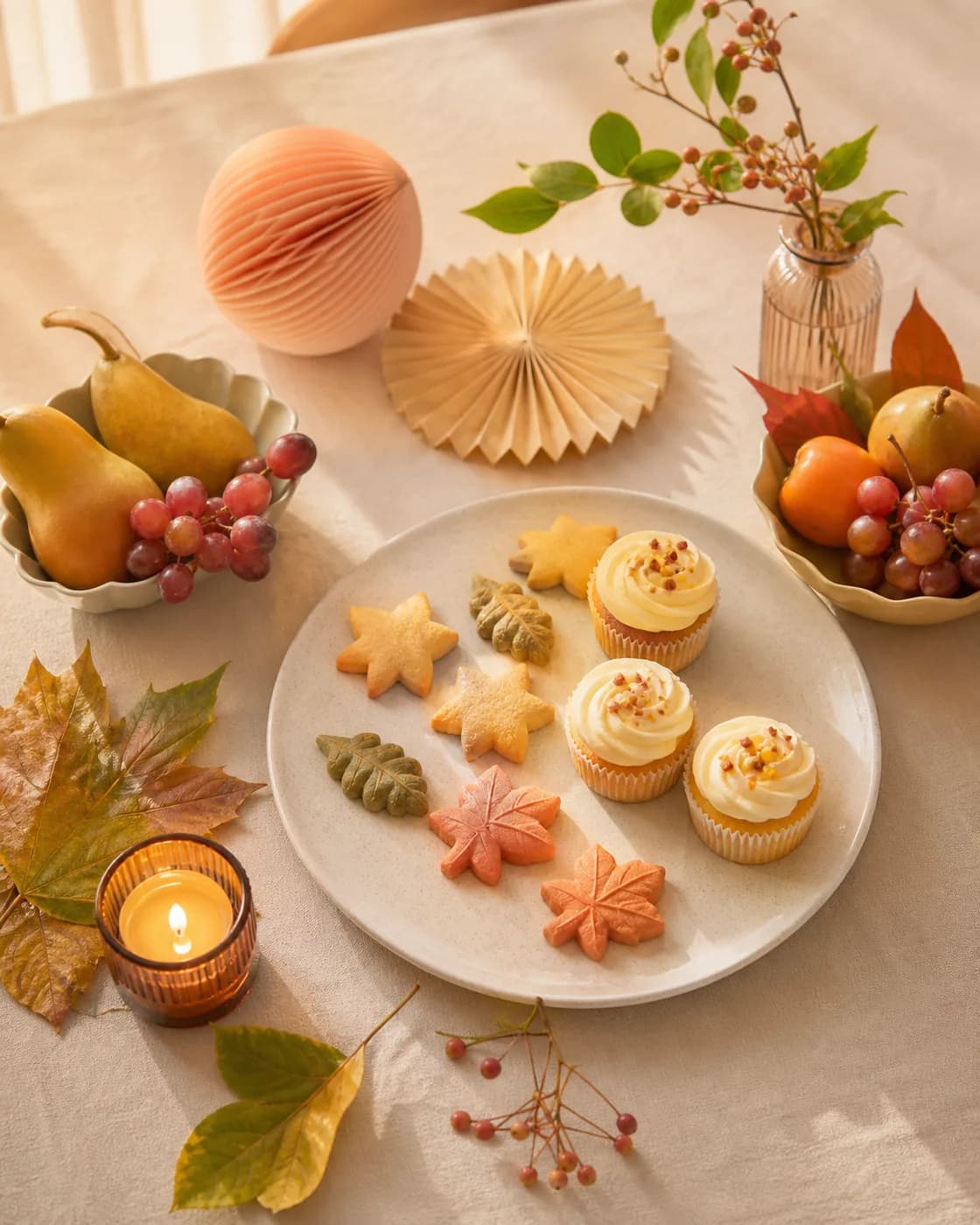 Mesa cálida con galletas, cupcakes, fruta y decoraciones de temporada